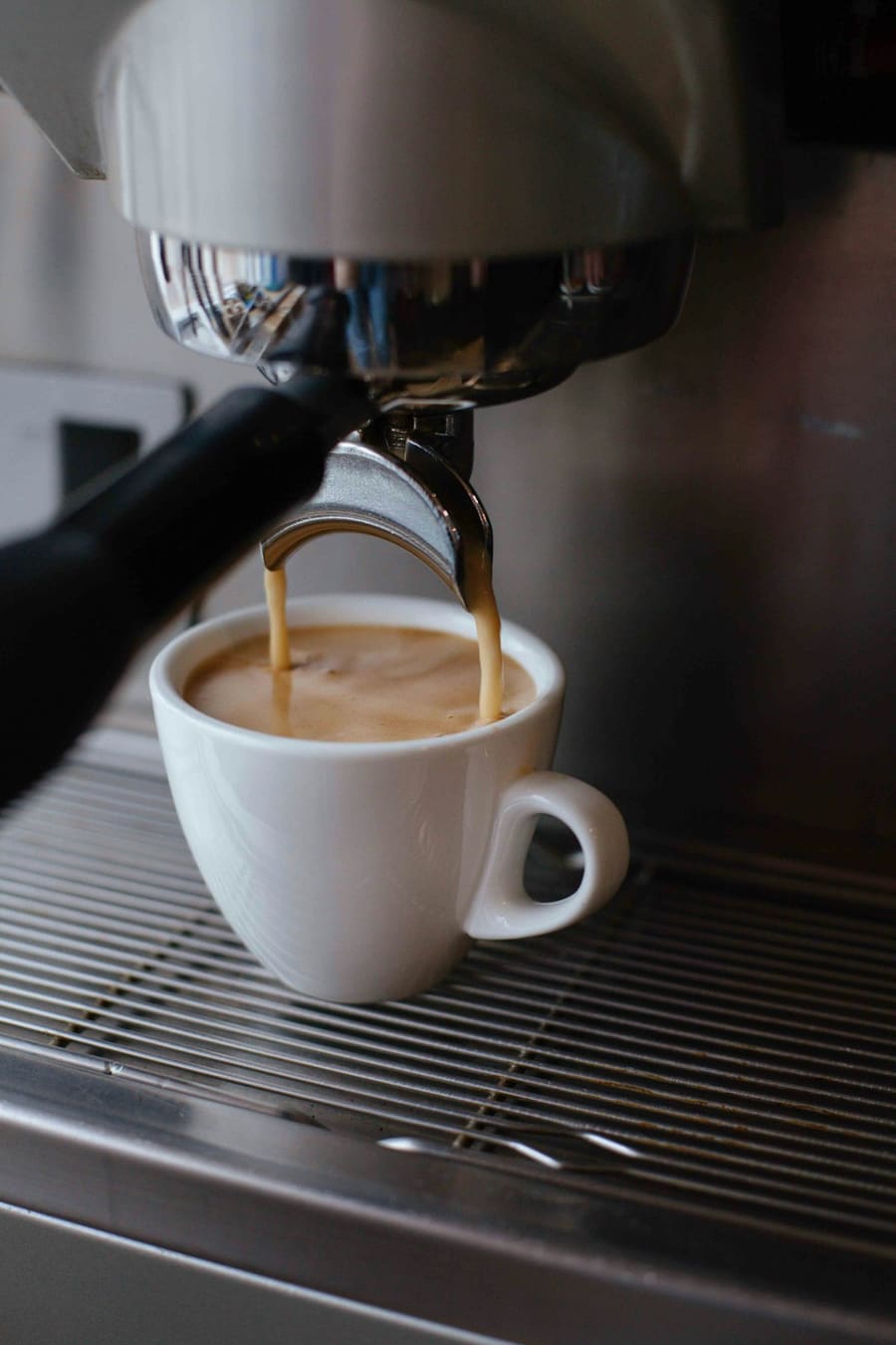 Espresso läuft in eine weiße Tasse auf dem Abtropfgitter