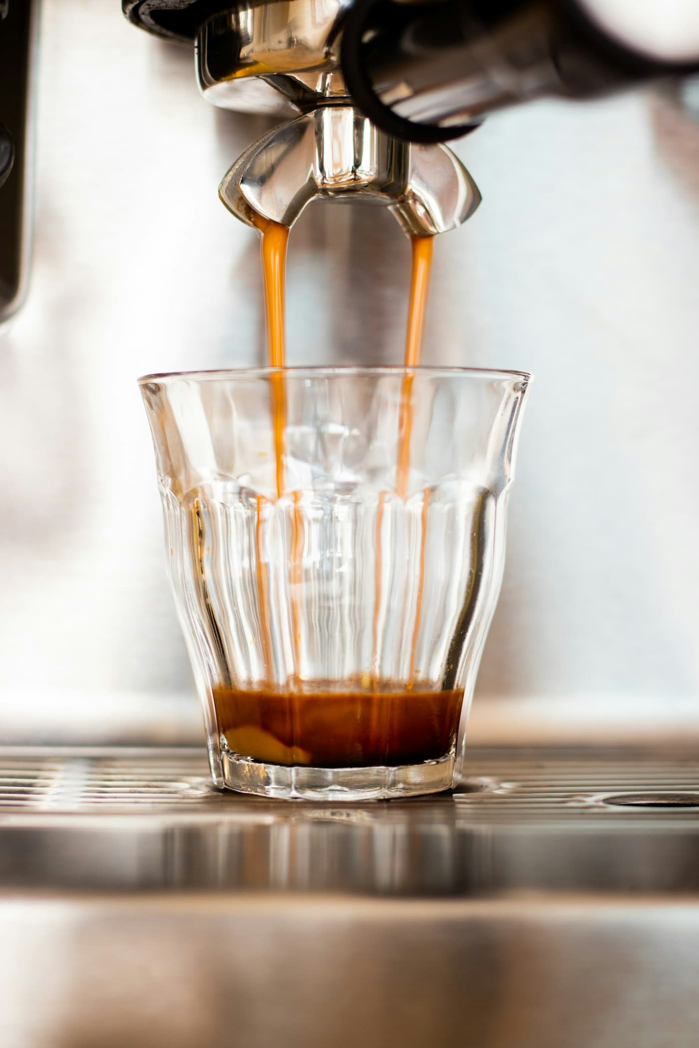 Espresso läuft in ein geriffeltes Glas auf dem Abtropfgitter